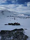 Snøscootere med personer i et åpent, snødekt fjellområde
