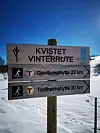 Skilt for kvistet vinterrute mot Gjevilvasshytta og Trollheimshytta i snødekt terreng.