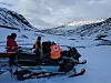 Redningsmannskap fra Røde Kors ved snøskuter i snødekte fjell