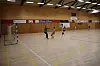 Spillere spiller håndball i en stor innendørs hall med mål og reklameskilt.