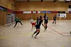 Spillere i håndballkamp i innendørshall med keeper foran målet