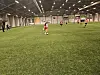 Ungdom spiller fotball på kunstgress i en innendørs fotballhall.
