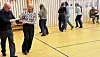 Flere par som danser i en gymsal med tregulv.