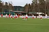 Fotballspillere i røde og hvite drakter feirer på kunstgressbane utendørs