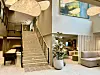 Lys hotellobby med trapp, store lamper og sittegrupper i moderne stil