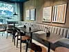 Moderne kafé med benk langs veggen, trebord og stor vindusrute mot fjell.
