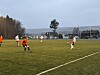 Fotballkamp på kunstgressbane mellom lag i oransje og hvite drakter en overskyet kveld