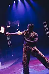 Ildkunstner i mønstret kostyme opptrer med flammer på sirkusscene.