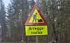 Varselskilt for anleggstrafikk ved skogkledd vei.