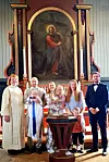 Familie og prest står rundt døypefonten med dåpsbarn i Rindal kyrkje.