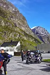 Motorsykler parkert ved hus og bratte fjell en solfylt dag