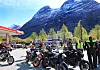 Flere motorsykler parkert ved Circle K-stasjon foran høye snødekte fjell