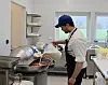 En person heller ingredienser i en stor mikser i et næringskjøkken.