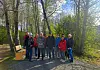 En gruppe mennesker står ved en skogsti omgitt av trær og grønn vegetasjon.