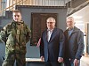 Tre menn står oppstilt foran en minneplakett i en hall.