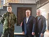 Tre menn står oppstilt foran en minneplakett i en hall.