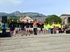 En gruppe står på steintrapper foran fjell og bygninger under en utendørs samling.