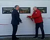 To menn står ved siden av en hvit dør og klipper en snor