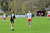 Fotballspillere står spredt på en grønn bane med benker og reklameskilt i bakgrunnen.