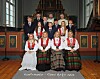 En gruppe konfirmanter og to geistlige står og sitter foran alteret i en kirke.