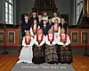En gruppe konfirmanter og to geistlige står og sitter foran alteret i en kirke.