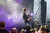 Gitarist spiller på scene foran publikum med lilla lys og røyk.