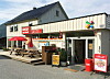 Coop-butikk med uteservering, piknikbord og inngang ved en stille vei.