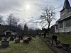 Personer jobber på en kirkegård ved en kirke under en lys, overskyet himmel.