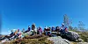 En gruppe mennesker på svaberg under blå himmel.