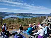 Gruppe mennesker sitter på en steinrygg med utsikt over innsjøer og fjellandskap.