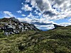 Steinete fjellandskap med gresskledde bakker og dramatisk skydekke.