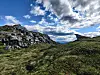 Steinete fjellandskap med gresskledde bakker og dramatisk skydekke.