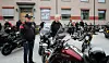 Flere motorsykler og personer står samlet foran en bygning på en grå dag.