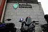 Surnadal kommune-skilt på en bygning med parkert scooter i forgrunnen.