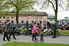 Syklister og fotgjengere i et boligområde med tilskuere langs veien og kommunale hus i bakgrunnen.