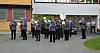Et brassband i uniformer spiller utendørs foran en bygning.