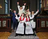 Konfirmanter står samlet foran alteret i en kirke og smiler med armene i været.