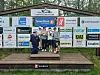 Barn står samlet foran en sponsorvegg med mange logoer ved et skianlegg.