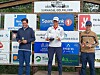 Tre menn står på en premiepall foran sponsorvegger, med Marius Kvande i midten med pokal.