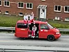 En rød russebil med folk på taket.