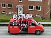 En rød russebil med folk på taket.
