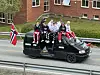 En svart russebil med folk på taket.