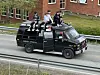 En svart russebil med folk på taket.