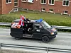 En svart russebil med folk på taket.