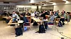 Studenter sitter ved bord med bærbare datamaskiner i et lyst bibliotek.