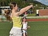 Ungdom i gul topp slår en volleyball på en friidrettsbane med en annen person i bakgrunnen.