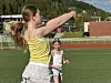 Ungdom i gul topp slår en volleyball på en friidrettsbane med en annen person i bakgrunnen.
