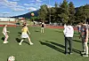 Ungdommer spiller med en volleyball på en kunstgressbane med fjell og trær i bakgrunnen.