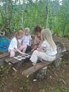 Fire barn sitter på en benk i skogen og spiller et brettspill.