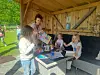 Barn og en voksen rundt et bord i en trepaviljong, med et fargerikt hefte og leker.